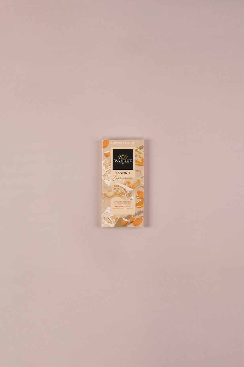 video tavoletta di cioccolato bianco al torrone si scarta e si divide, su sfondo neutro e decorato con torroni e mandorle