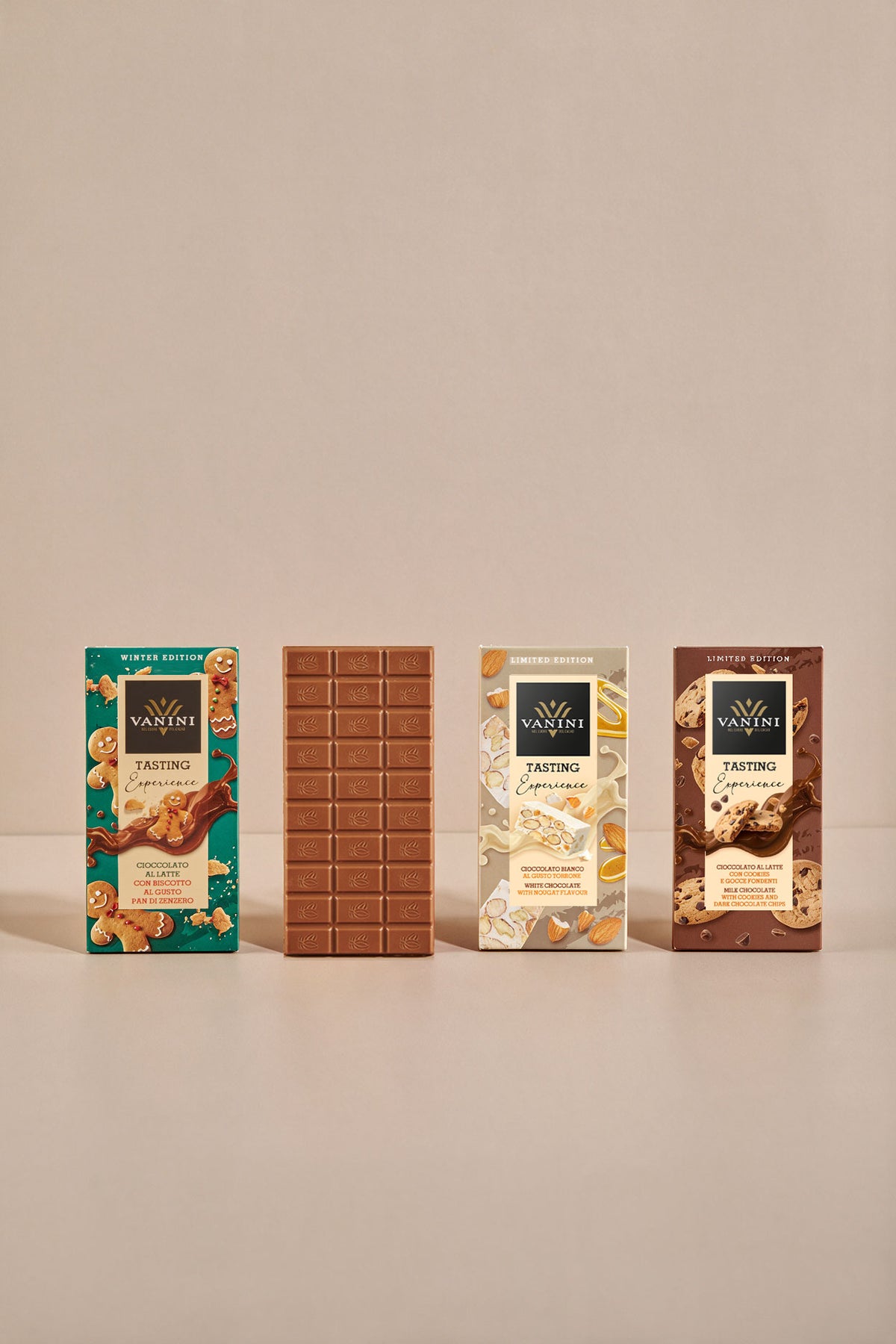 Assortimento Vanini Tasting Experience Winter Edition con quattro referenze di cioccolato ispirate ai dolci delle festività. Al centro della composizione è esposta una tavoletta di cioccolato al latte aperta, che mostra il caratteristico stampo Vanini. Le confezioni celebrano gusti come pan di zenzero, torrone e biscotti con gocce di cioccolato, con grafiche raffinate e ingredienti illustrati su sfondo chiaro e minimalista.