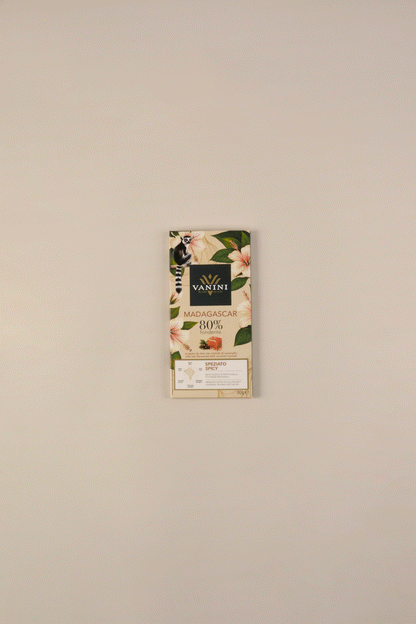 Video in cui la tavoletta di cioccolato fondente si scarta e si divide in pezzi. con affianco foglie di te chai e caramello. tutto su sfondo neutro beige.